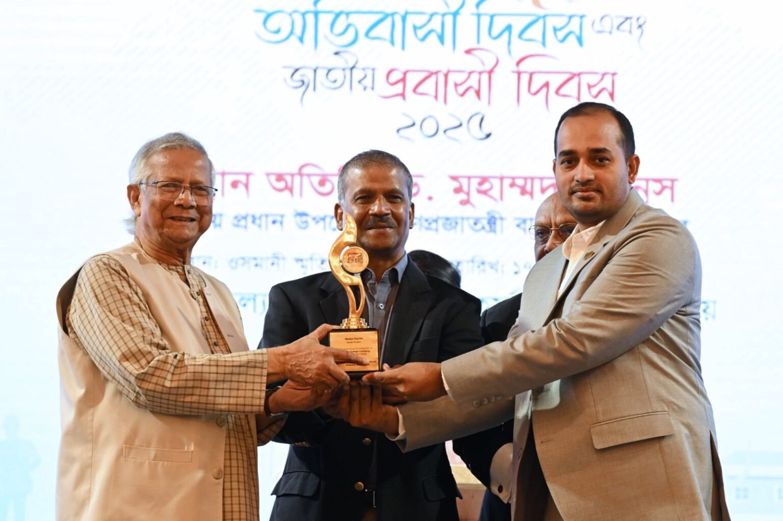 আন্তর্জাতিক অভিবাসী দিবস ও জাতীয় প্রবাসী দিবস উপলক্ষে বুধবার (১৭ ডিসেম্বর) ঢাকার ওসমানী স্মৃতি মিলনায়তনে আয়োজিত অনুষ্ঠানে তিনজন প্রবাসীকে বাণিজ্যিক গুরুত্বপূর্ণ ব্যক্তি হিসেবে সম্মাননা স্মারক দেওয়া হয়। তাঁদেরই একজনকে প্রধান উপদেষ্টা অধ্যাপক মুহাম্মদ ইউনূসের হাত থেকে স্মারকটি গ্রহণ করতে দেখা যাচ্ছে এই দৃশ্যে। [ছবি: প্রধান উপদেষ্টার কার্যালয়]